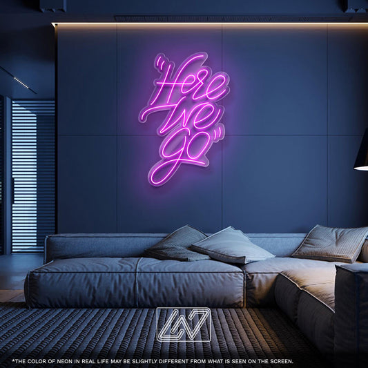 Neon sign saying "Here We Go" in a stylish living room setting.